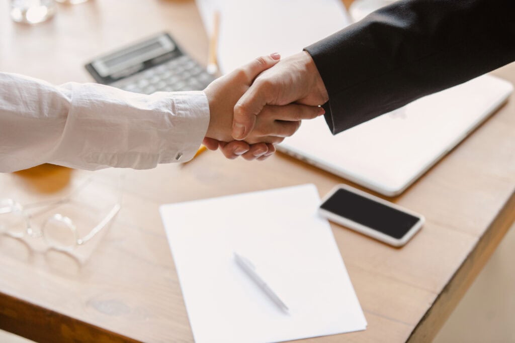 Conclusion of agreement, contract. Close up of caucasian human hands shaking, working in office.