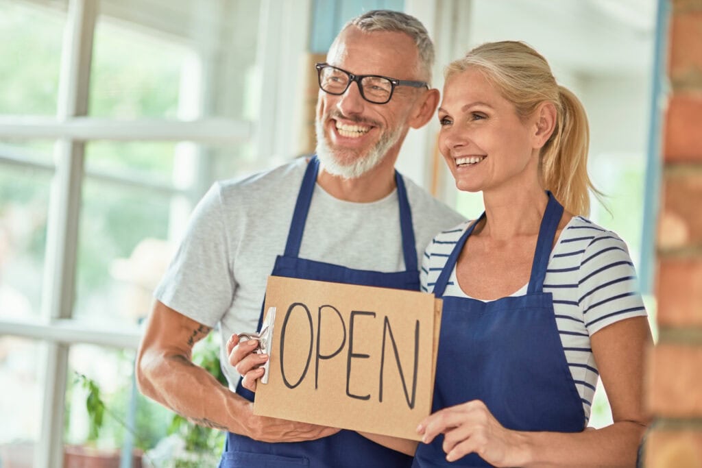 Couple holding an open sign for their small business